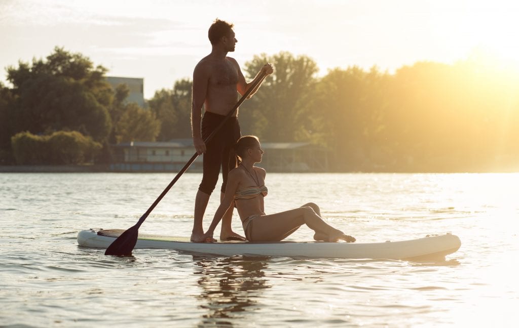 sports man and woman on vacation sport on stand up paddle board SUP newlyweds